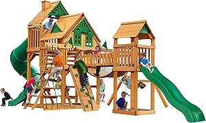 Children play on a large wooden swing set structure with slides, climbing walls, and rope ladders.