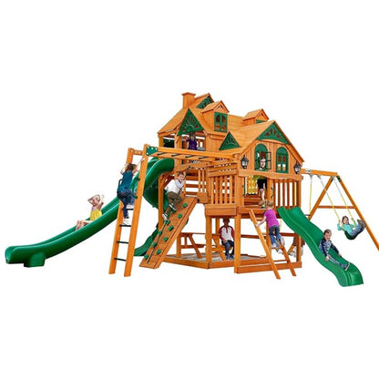 Several children play on a Gorilla Playsets Empire Extreme Wooden Swing Set with Monkey Bars, Clatter Bridge, Tower, and 3 Slides. The set features green and brown accents, swings, slides, climbing areas, and multiple activity zones.