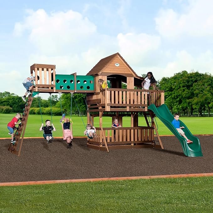 Children playing on a wooden playset with a slide, swings, climbing ladder, and lookout tower on a green lawn.