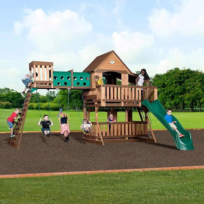 Children playing on a wooden playset with a slide, swings, climbing ladder, and lookout tower on a green lawn.